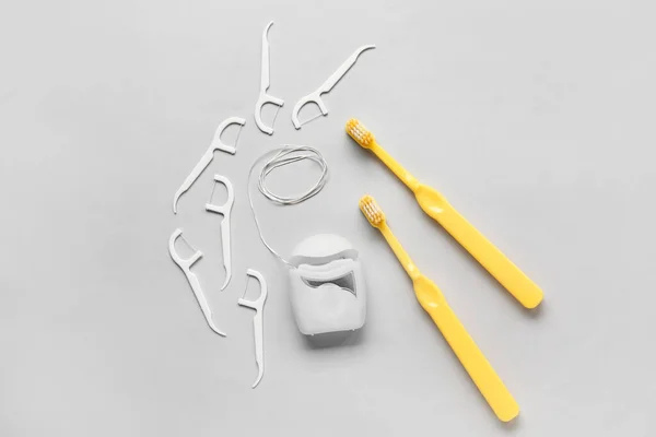 Dental floss, toothpicks and brushes on light background