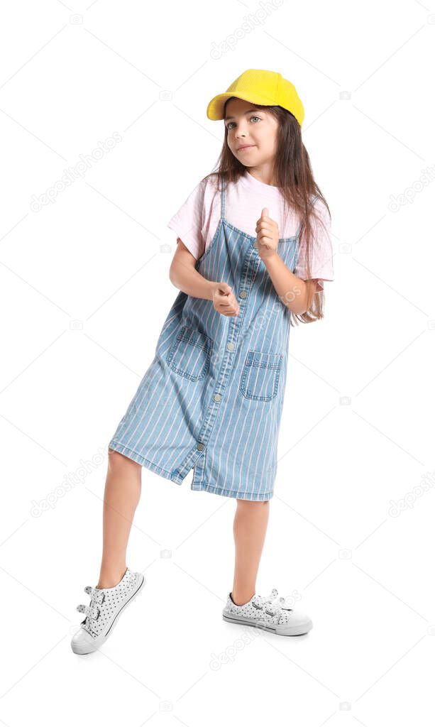 Adorable little girl in pinafore dancing on white background