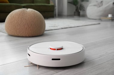 Odanın ahşap zemininde modern robot elektrikli süpürge.