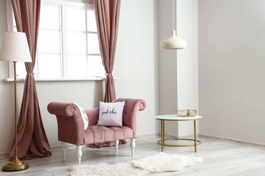 Pembe koltuklu, masalı ve lambalı aydınlık oturma odasının içi.