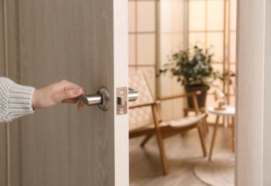 Evdeki açık tahta kapıyı açan kadın, yakın plan.