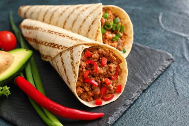 Esmer arka planda lezzetli dürümler ve sebzeler, yakın plan.