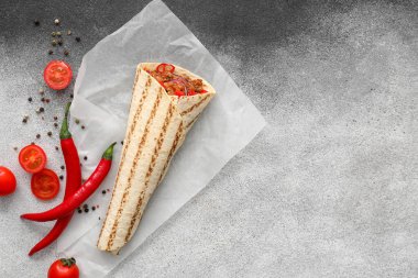 Lezzetli burrito, sebze ve baharatlar gri arka planda.