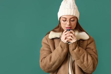 Kışın giyinmiş güzel bir kadın ve bir fincan kahveyle renklendirilmiş bir arka plan