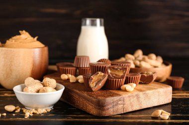 Koyu ahşap arka planda fıstık ezmeli lezzetli çikolata şekerleri olan tahta.