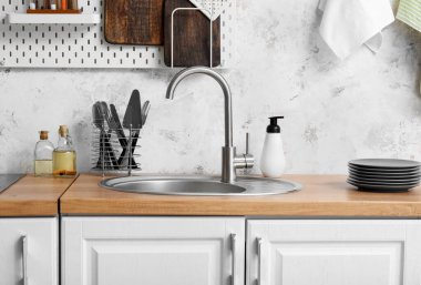 Gümüş lavabolu ahşap tezgah ve mutfak lambasının yanındaki çatal bıçaklar.