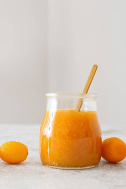 Kavanoz dolusu lezzetli kumkat reçeli ve mutfak masasında taze meyve.