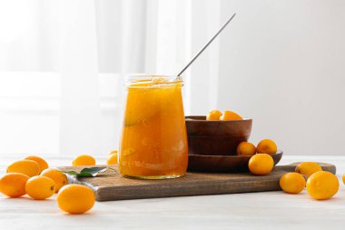 Kavanoz dolusu lezzetli kumkat reçeli ve mutfak masasında taze meyve.