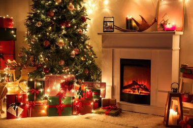 Güzel Noel ağacı olan bir şömine ve geceleri oturma odasında hediyeler.