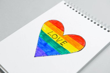 Açık arkaplanda çizilmiş gökkuşağı kalbi olan bir defter. LGBT kavramı
