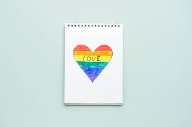 Açık arkaplanda çizilmiş gökkuşağı kalbi olan bir defter. LGBT kavramı