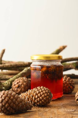 Lezzetli bir kavanoz kozalak reçeli ve ağaç dalları ahşap masada.