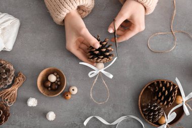 Gri arka planda el yapımı Noel oyuncakları yapan kadın.