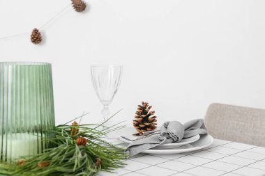 Beyaz duvarın yanında çam kozalakları ve köknar dallarıyla güzel bir masa.