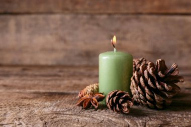 Ahşap zemin üzerinde kozalaklı yanan mum.