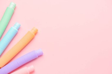 Pembe arka planda farklı renkli pop tüpleri