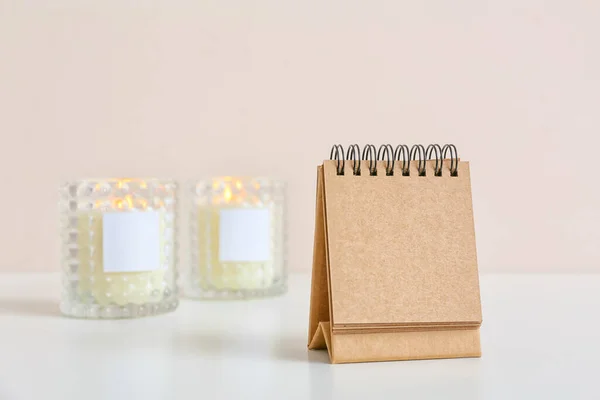 浅色背景下的空白工艺日历和桌上点燃的蜡烛 — 图库照片