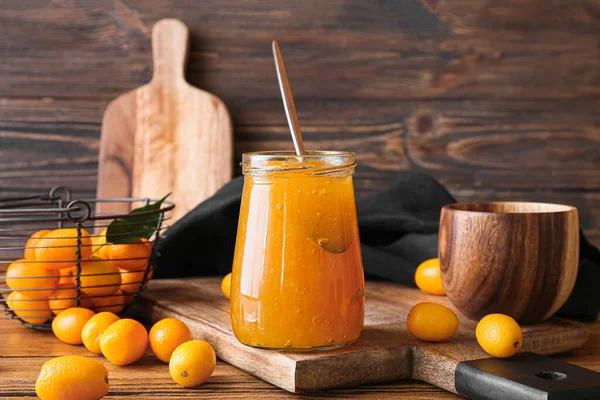 Bir kavanoz lezzetli kumkat reçeli ve ahşap zemin üzerinde taze meyveler.