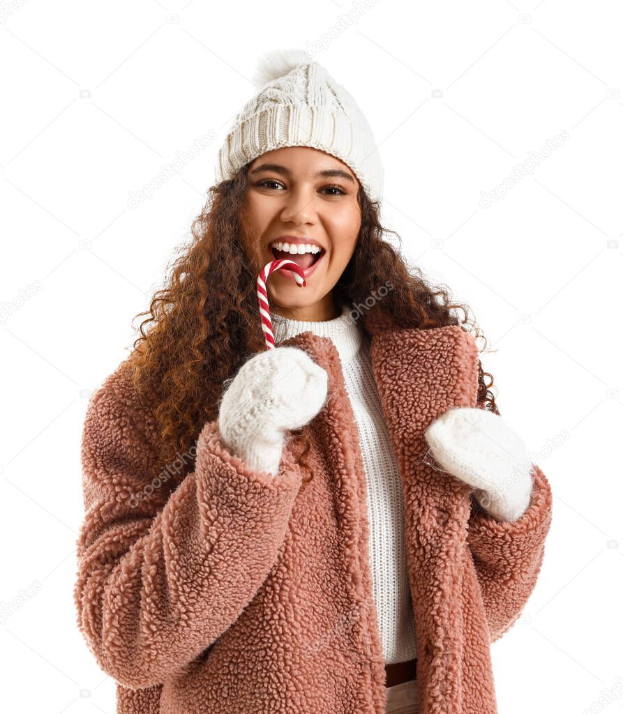 Beautiful young woman in stylish winter clothes and with candy cane on white background