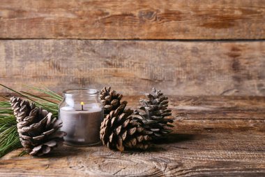 Ahşap zemin üzerinde yanan mum ve çam kozalakları olan tutucu