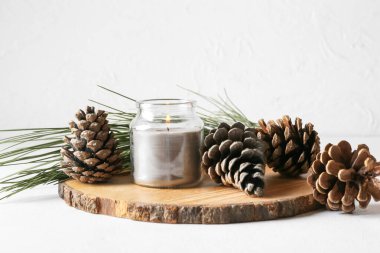 Çam kozalaklı tahta, yanan mum ve arka planda köknar dalı