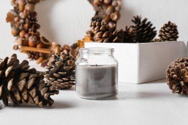 Işıklı arka planda yanan mum ve çam kozalaklı cam tutucu, yakın plan