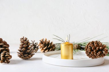 Işık arka planında yanan mum ve çam kozalaklarıyla dur