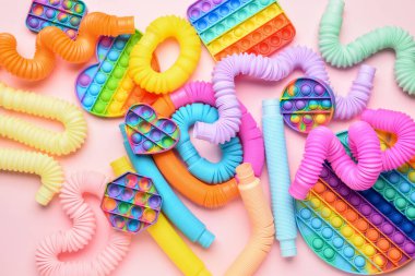 Renkli pop tüpleri ve patlayan oyuncaklar pembe arka planda