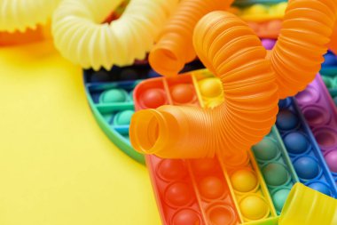 Renkli pop tüpleri ve patlayan oyuncaklar sarı arka planda