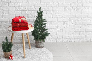 Odanın içinde kışlık giysiler ve Noel ağaçları olan masa.