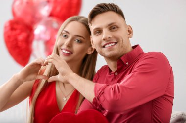 Mutlu çift evde elleriyle kalp şekillendiriyor. Sevgililer Günü kutlaması