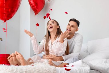 Sevgililer gününü evde, yatak odasında kutlayan mutlu çift.