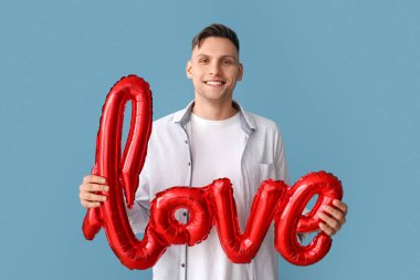 Balonlu genç bir adam. Renkli arka planda aşk kelimesi var. Sevgililer Günü kutlaması