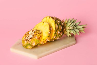 Pembe arka planda taze kesilmiş ananas tahtası