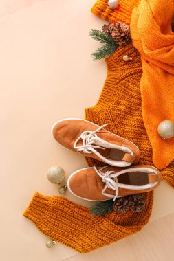 Örgü süveter, atkı, şık ayakkabılar ve arka planda Noel dekoru.
