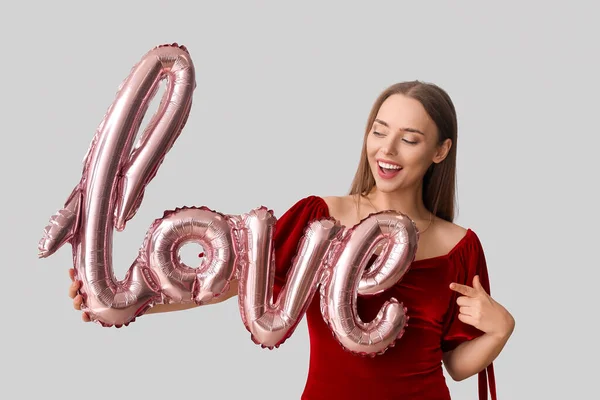 Młoda Kobieta Balonem Kształcie Słowa Love Szarym Tle Święto Walentynek — Zdjęcie stockowe