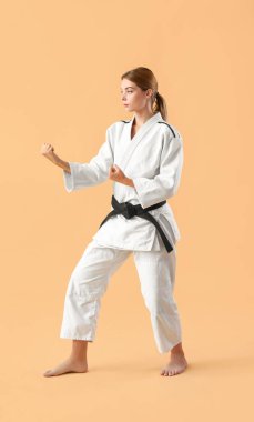 Genç bir kadın renk geçmişinde karate yapıyor.