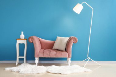 Masa ve lambalı rahat koltuklar mavi duvarın yanında.