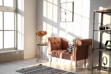 Işık duvarının yanındaki vazoda kurumuş çiçekli pembe koltuk ve masa.