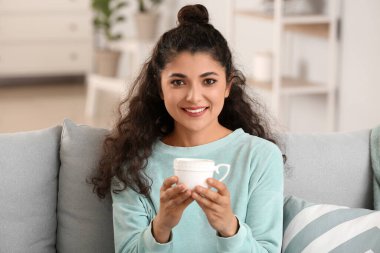 Evde çay içen güzel bir kadın.