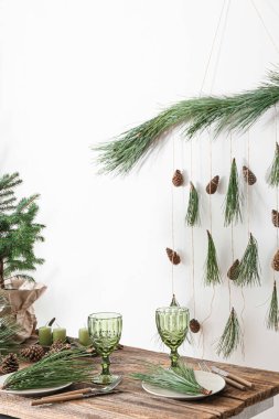 Beyaz duvarın yanında çam kozalakları ve köknar dallarıyla güzel bir masa.