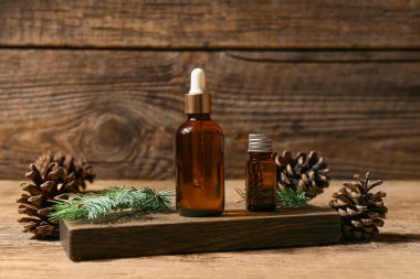 Ahşap zemin üzerinde gerekli yağ şişeleri, köknar dalı ve çam kozalakları olan tahta tahta.