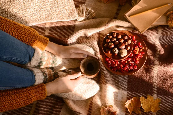 Женщина Теплых Носках Чашкой Кофе Едой Осенними Листьями Клетчатом Фоне — стоковое фото
