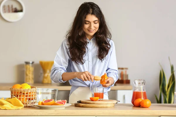 在厨房里做新鲜柑橘汁的年轻女人 — 图库照片