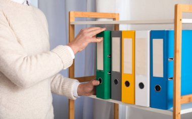 Ofiste belgelerle çalışan genç adam.