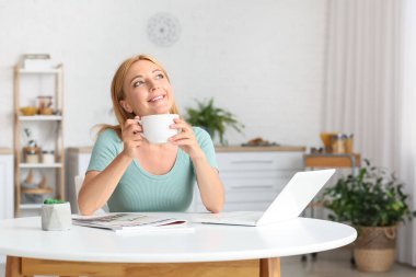 Güzel olgun kadın evde kahve içiyor.