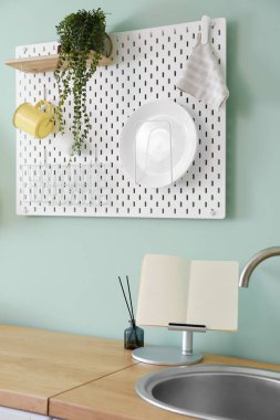 Tabakları ve yeşil duvarda asılı çiçekleri olan tahta tahta.