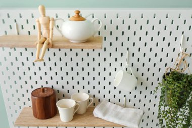 Tabakları, ahşap mankeni ve yeşil duvarda asılı bitki örtüsü olan tahta tahta tahta tahta tahta tahta.