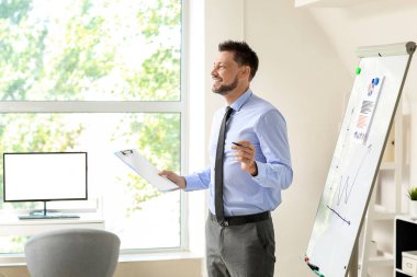 Yakışıklı bir iş adamı ofisteki tablonun yanında sunum yapıyor.