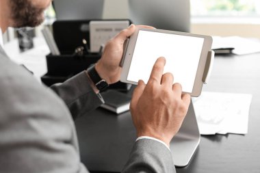 Ofisteki tablet bilgisayarla çalışan genç işadamı, yakın plan.